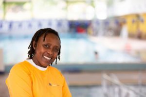An African woman wearing a swimming instructor's outfit at a swimming pool