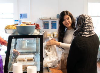 Two women stand in front of a food counter at the Asylum Seekers Centre