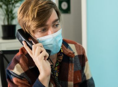 A man wearing a mask speaks on the phone.