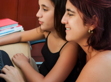 A woman helps her daughter with a task on the computer