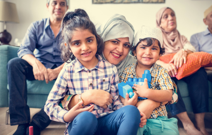 A Muslim woman crouches holding her two young children.