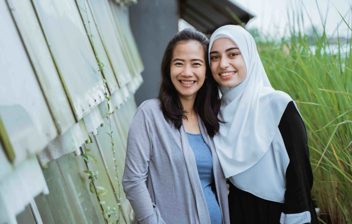 Two women stand outside near long grass