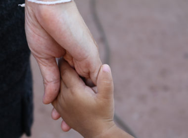 An adult's hand holding a child's hand.