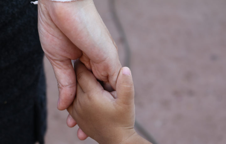 An adult's hand holding a child's hand.