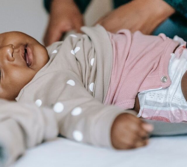 A baby lies down while having their nappy changed
