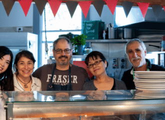 Five volunteers stand and smile in the ASC's industrial kitchen