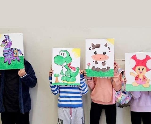 children holding up canvas paintings